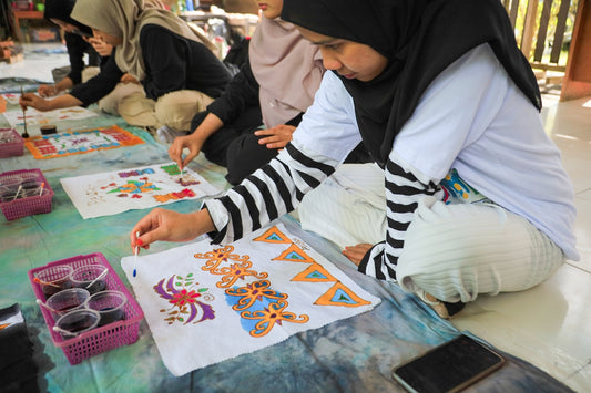 Women painting batik designs on fabric